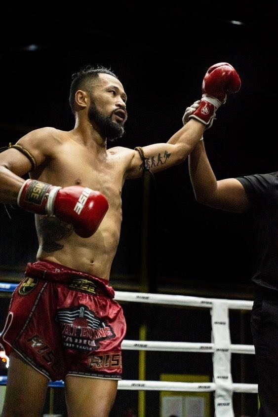 ครู Jason Somchay of Somchay Muay Thai in the ring, one arm raised.